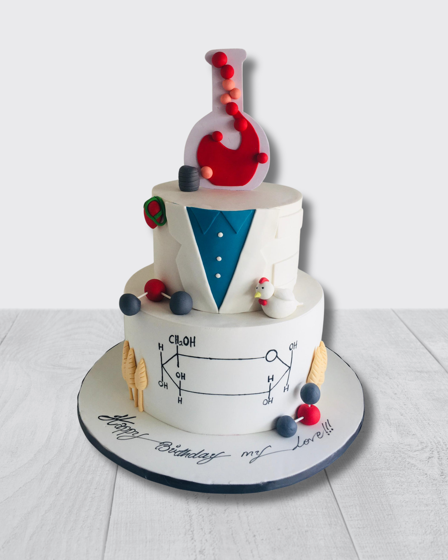 Two-tier birthday cake with scientific theme on a white background