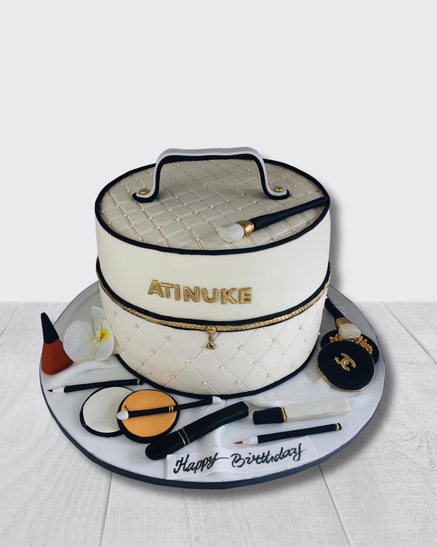 Cake designed like a makeup bag with cosmetic items on a white background