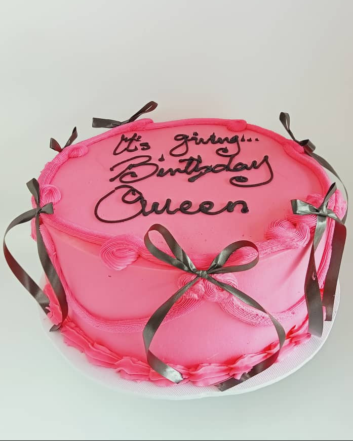 Pink cake with decorative ribbons and text on a white background
