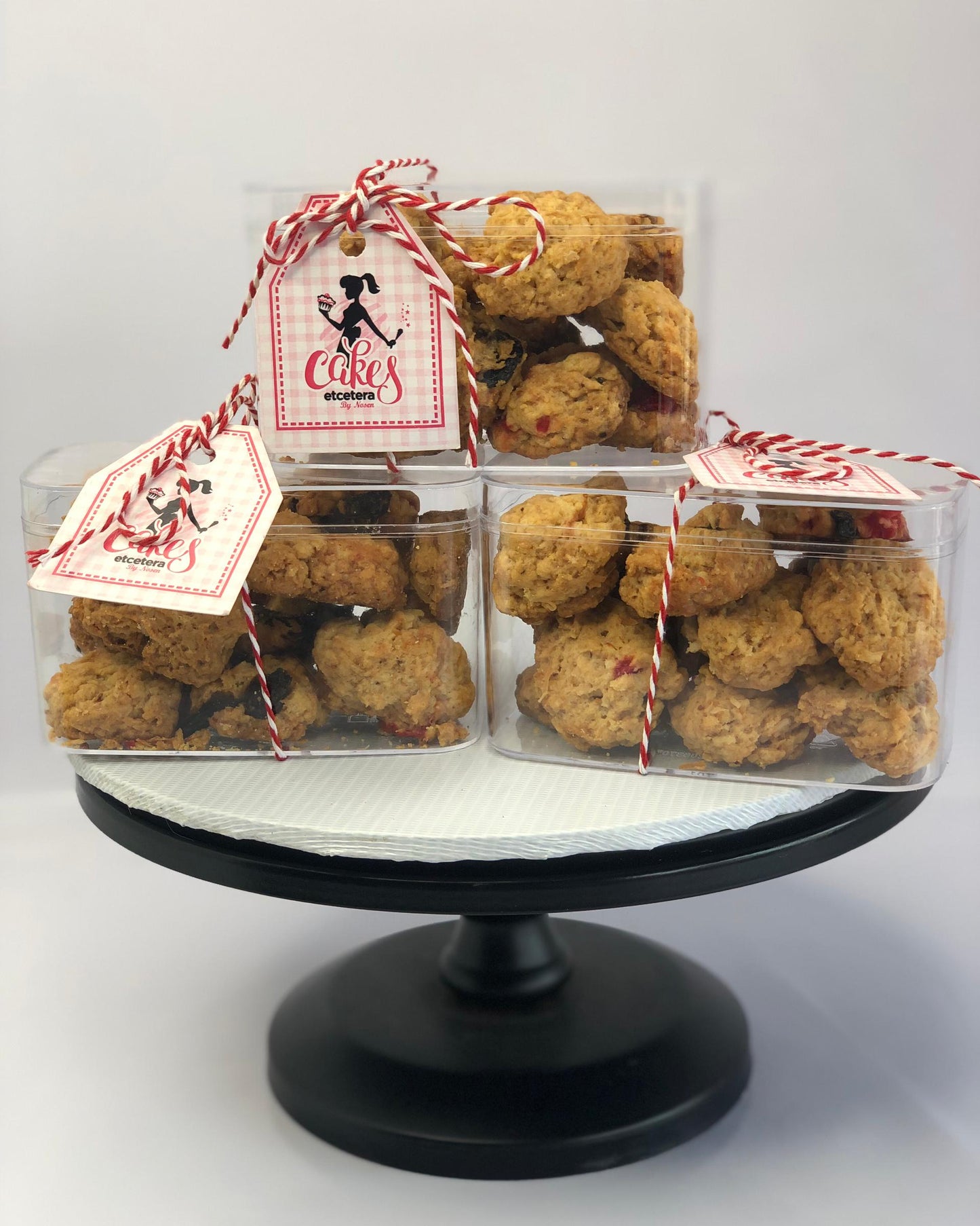 Three clear containers with rock buns on a black stand, branded 'The Cake Eater'.