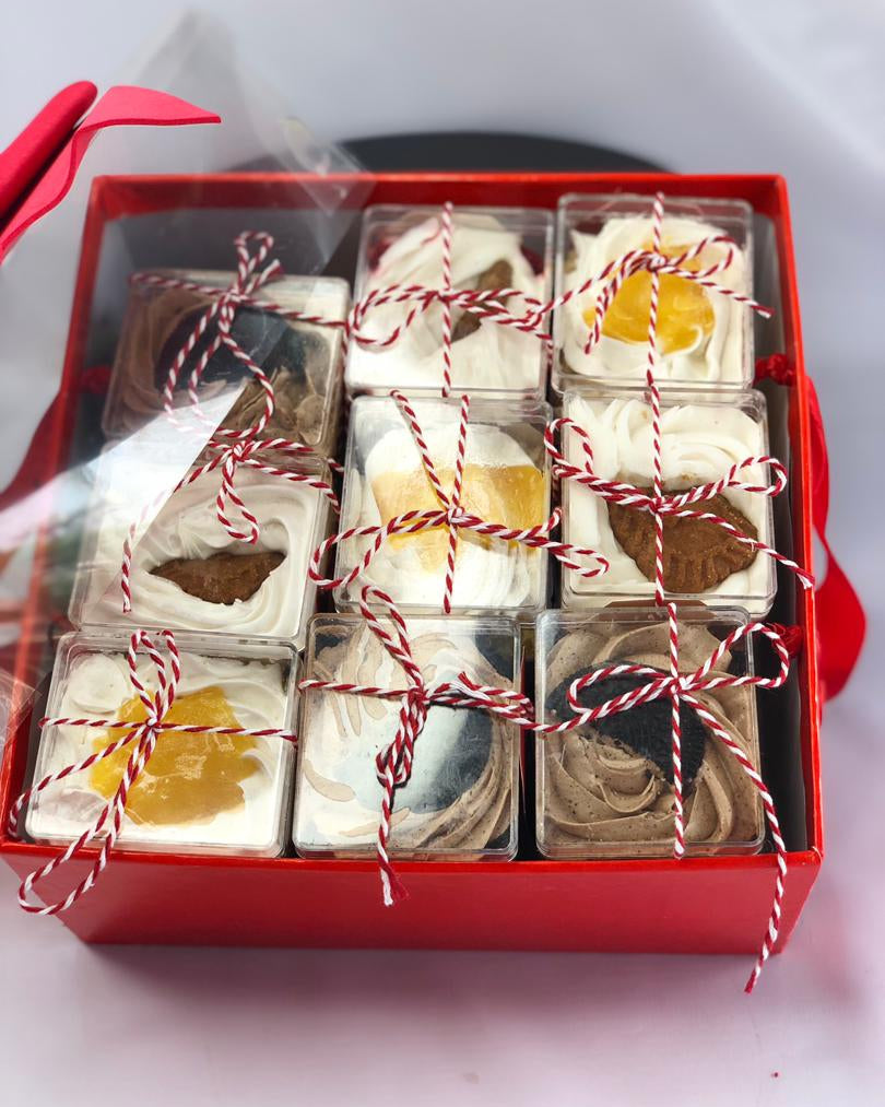 Box of assorted cake trilfe with red string ties on a white background