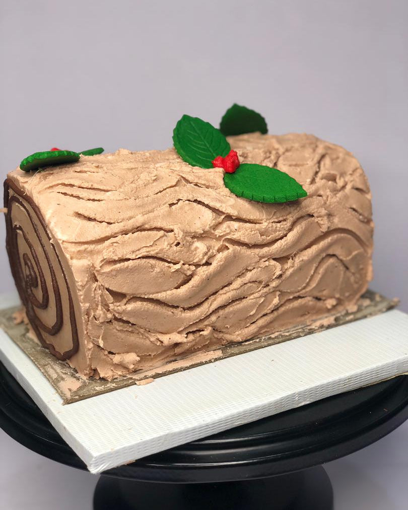 Chocolate log cake with holly decorations on a white background
