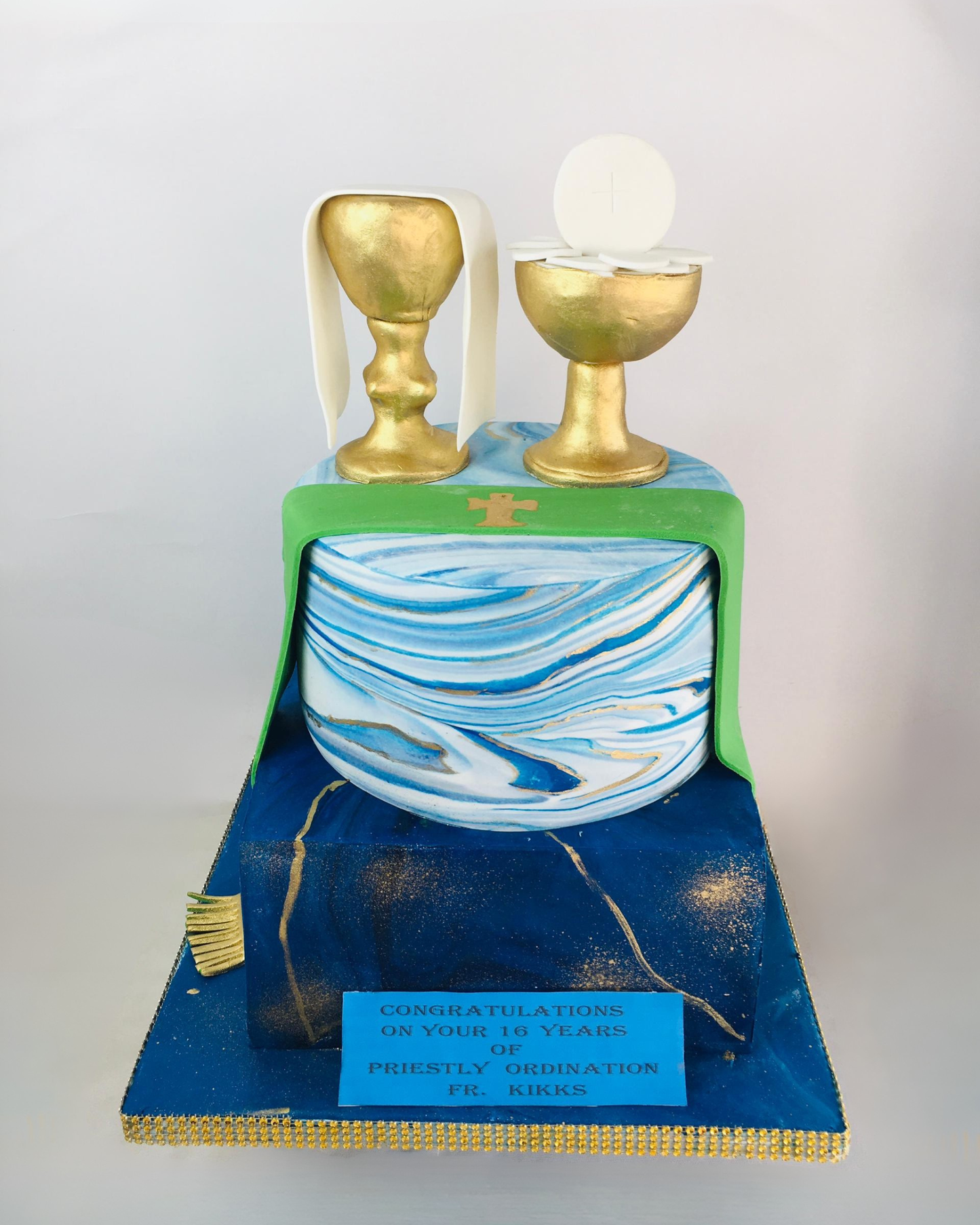 Priestly Decorative cake with gold goblets and blue and white marbled design on a white background