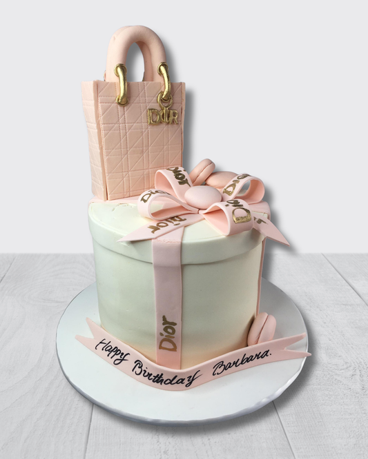 Cake designed like a Dior handbag with ribbons and text on a white background
