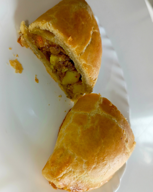 Half-eaten meatpie on a white plate