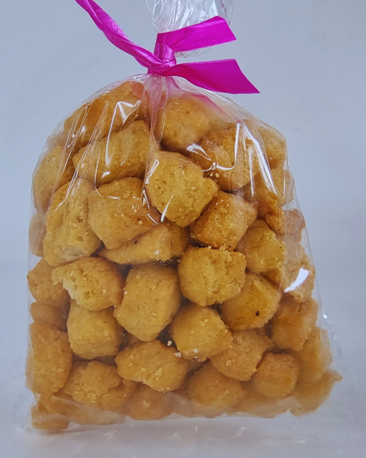 Clear bag filled with yellow chin chin tied with a pink ribbon on a white background