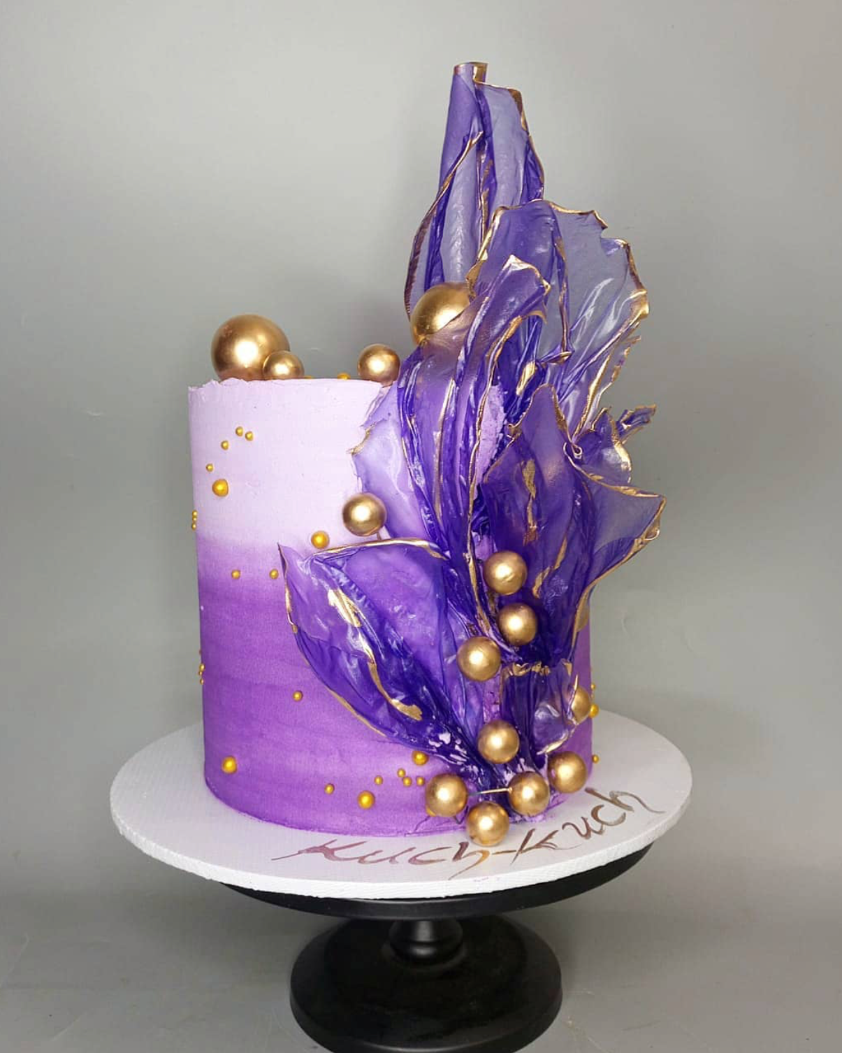Decorative cake with purple and gold design on a gray background