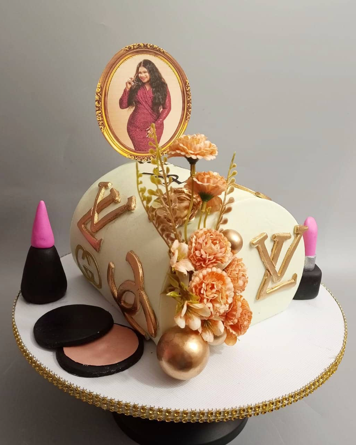 Makeup-themed cake with decorative elements and a portrait on top