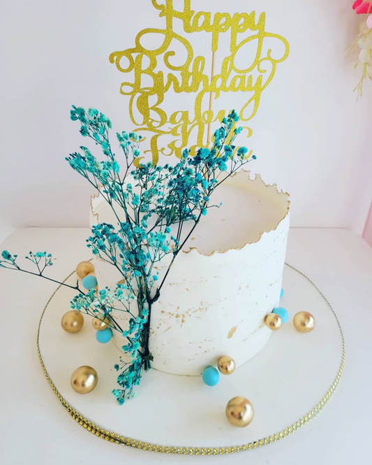 Birthday cake with decorative elements and 'Happy Birthday' topper on a white background