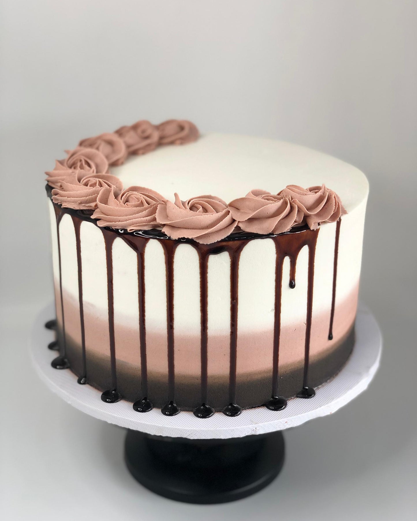 Chocolate cake with pink frosting and chocolate drizzle on a white background