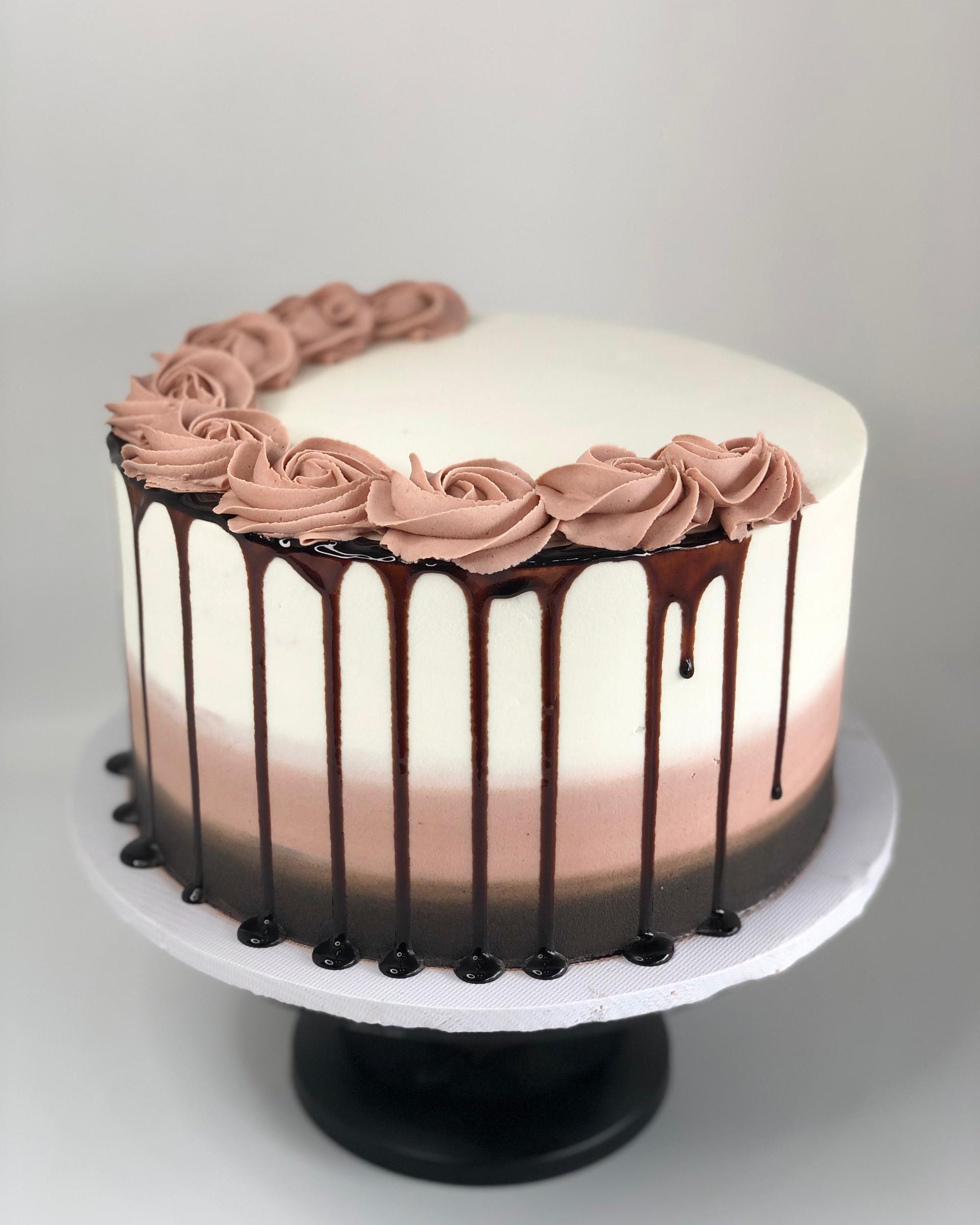 Chocolate cake with pink frosting and chocolate drizzle on a white background