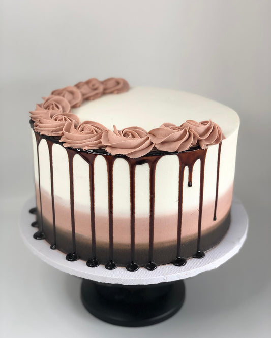 Chocolate cake with pink frosting and chocolate drizzle on a white background