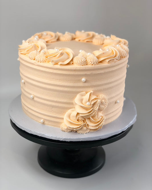Beige cake with decorative swirls on a gray background
