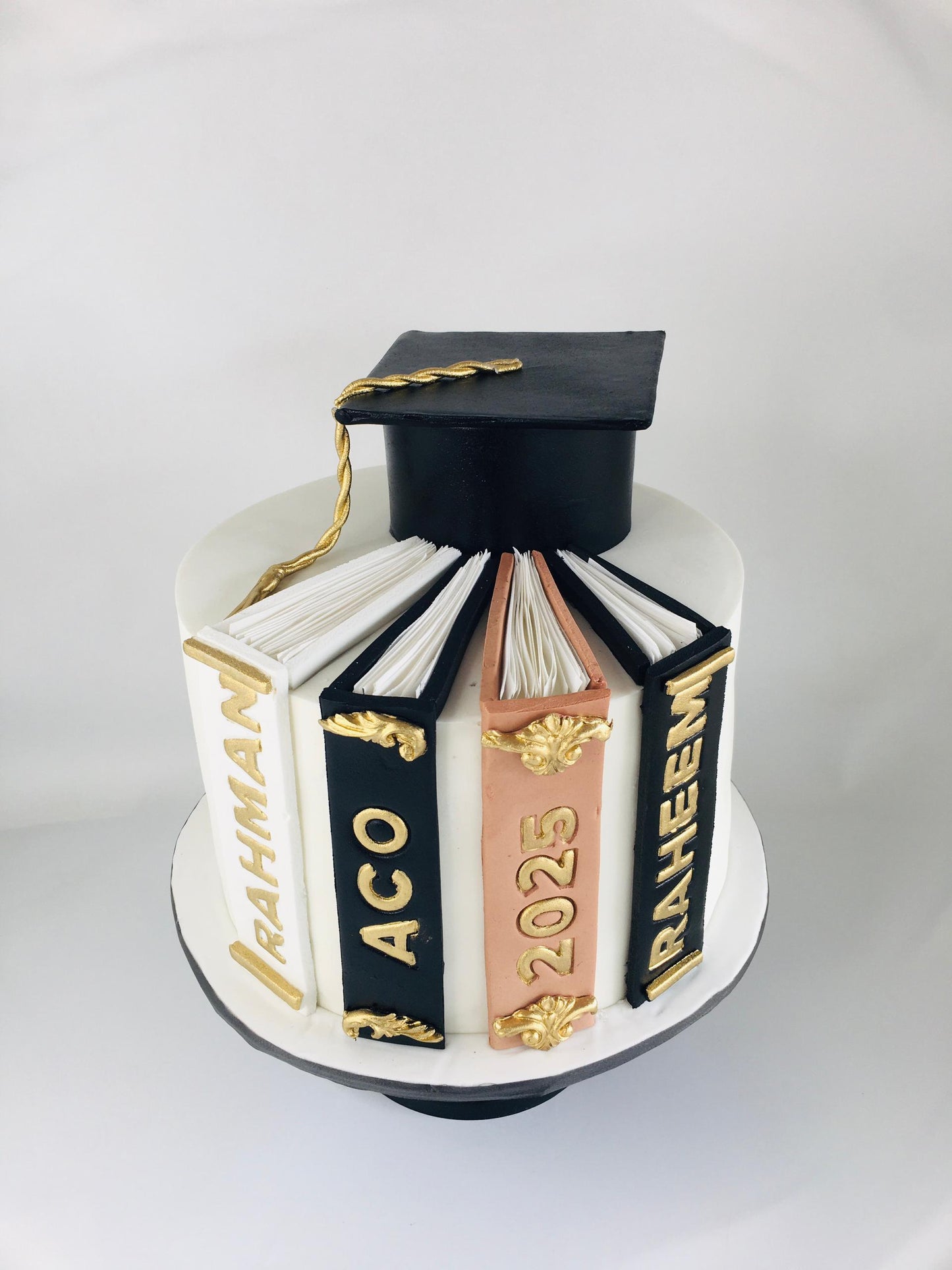 Graduation-themed cake with books and a cap on a white background