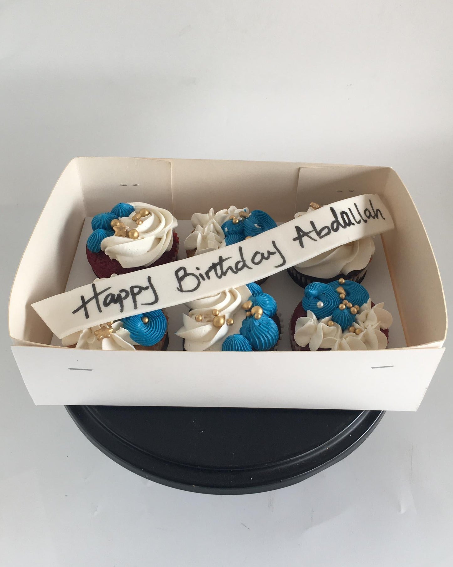 Box of cupcakes with a personalized birthday message on a white background