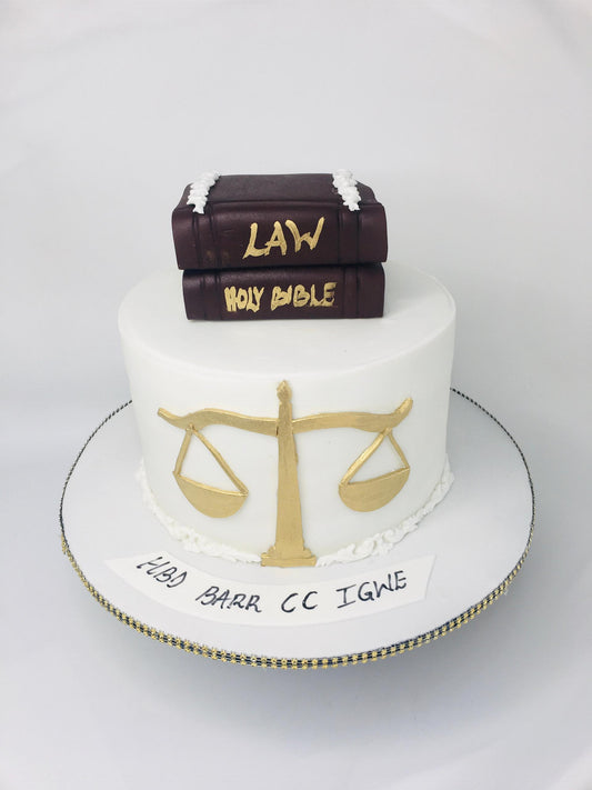 Cake with books labeled 'Law' and 'Holy Bible', scales of justice, and text on a white background