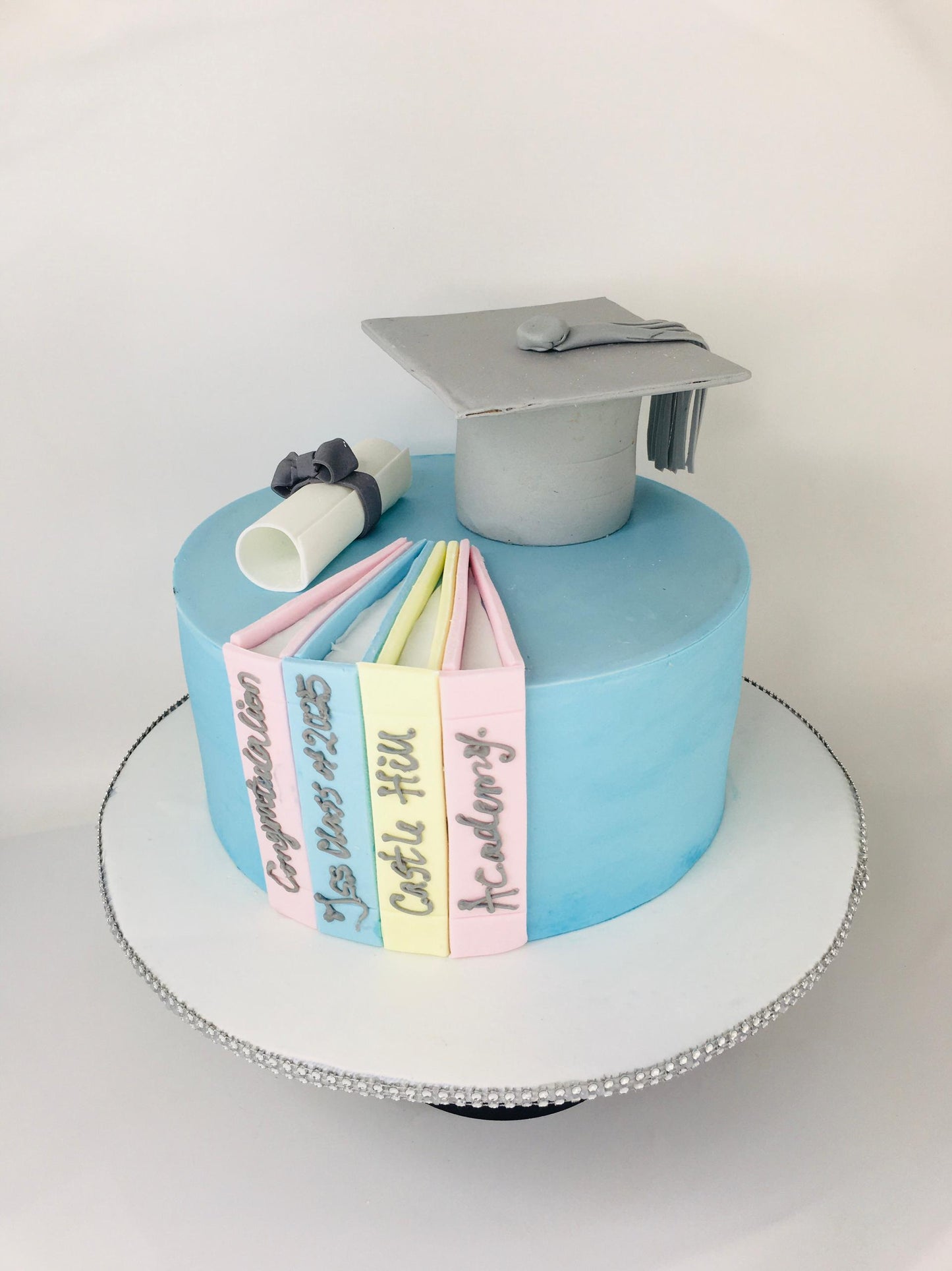 Graduation-themed cake with books and a cap on a white background