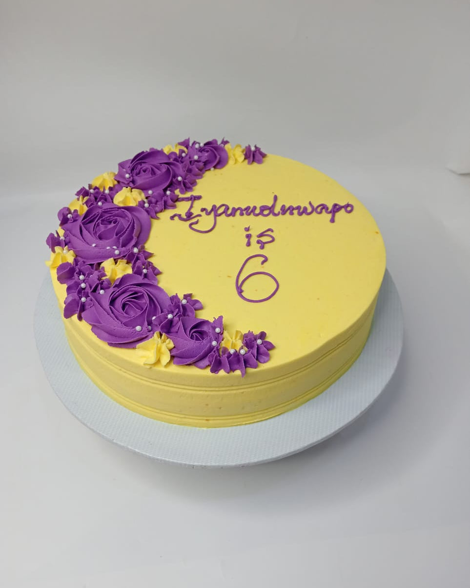 Yellow cake with purple floral decorations on a white background