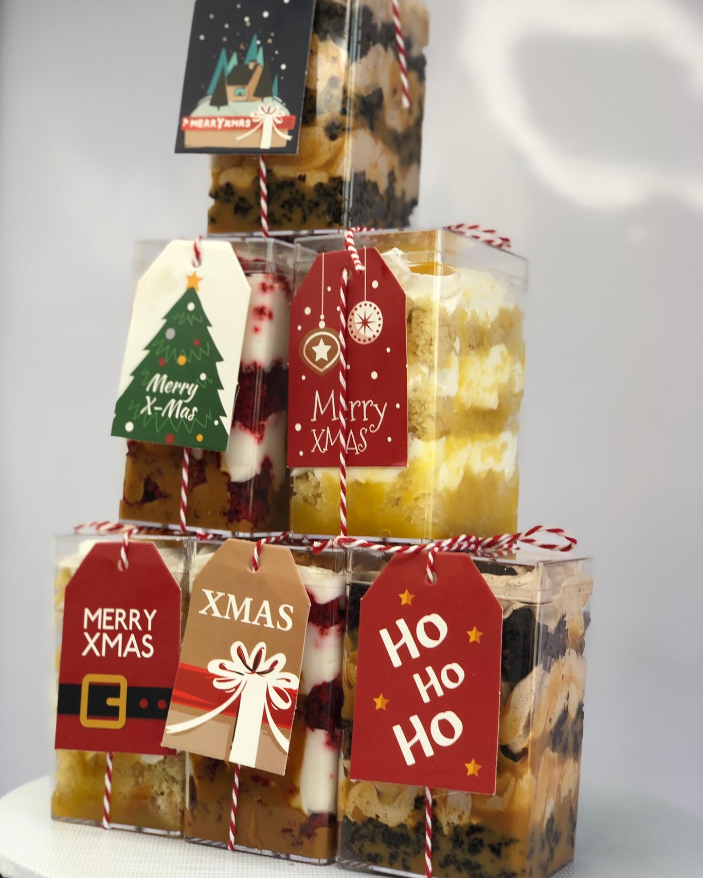 Stack of Christmas-themed gift boxes with decorative tags on a white background