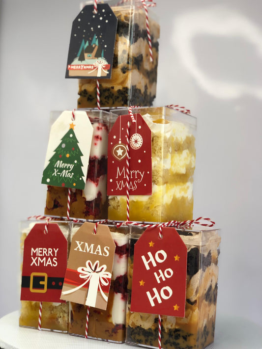 Stack of Christmas-themed gift boxes with decorative tags on a white background